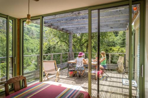 2 enfants assis à une table sur une terrasse couverte dans l'établissement Les chambres de la Dourbie, à Nant