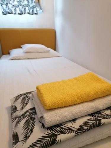 a bed with a yellow blanket and towels on it at Apartman Centar 2 in Kruševac