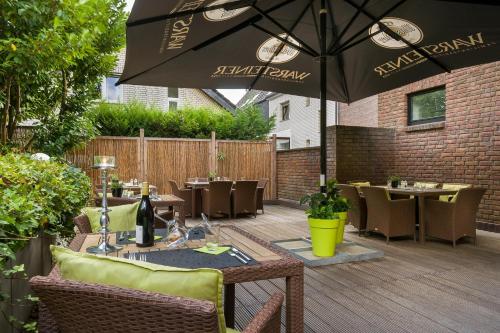 a patio with tables and chairs and an umbrella at Hotel Freiraum in Mönchengladbach