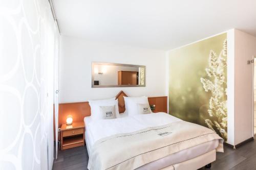 a bedroom with a white bed and a mirror at Hotel Freiraum in Mönchengladbach