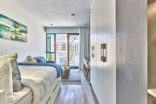 ein Schlafzimmer mit einem Bett und einem großen Fenster in der Unterkunft Contemporary arty Studio Balcony Mountain views in Kapstadt