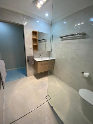 een badkamer met een glazen douche en een wastafel bij Waterside Canal Dreams in Mandurah