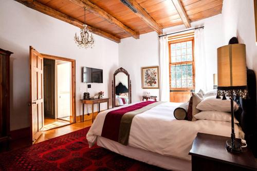 a bedroom with a large bed and a mirror at Cape Dutch @ Keerweder in Franschhoek