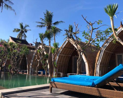 a resort with a swimming pool and a blue couch at Paradesa Villa in Gili Trawangan