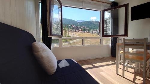 a living room with a couch and a large window at Le Portillo in Puy-Saint-Vincent