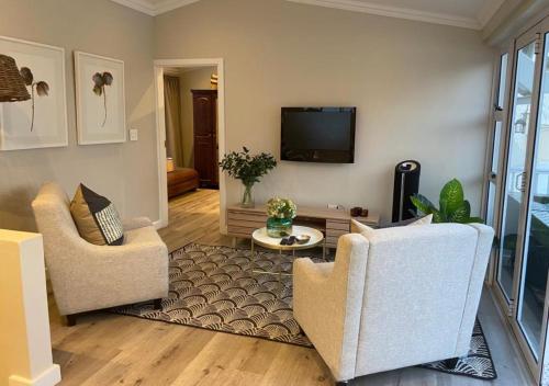 a living room with two chairs and a flat screen tv at The Loft on Monteith in Durban