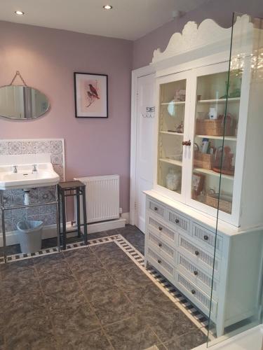 a bathroom with a sink and a glass cabinet at Ideally located Cumbrian home with stunning views in Seascale