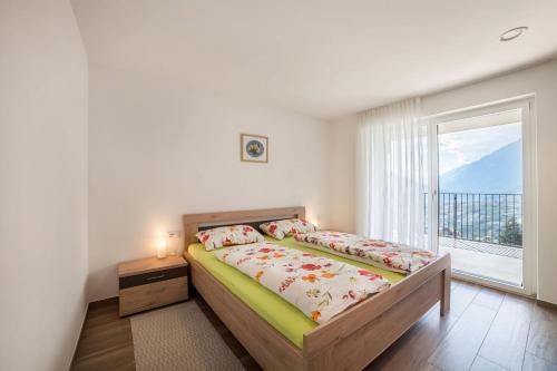 ein Schlafzimmer mit einem Bett und einem großen Fenster in der Unterkunft Panoramawohnung Bergerweg in Schenna