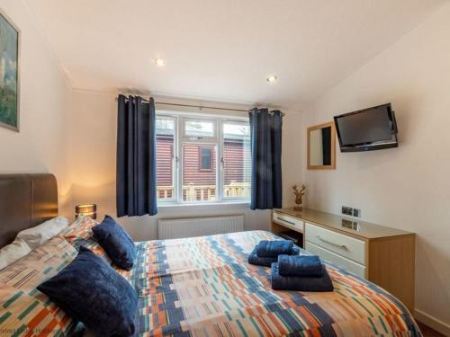 a bedroom with a bed with blue pillows on it at Windermere Retreat - White Cross Bay Holiday Park in Windermere