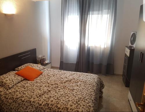 a bedroom with a bed with an orange pillow on it at Piso Granada in Granada