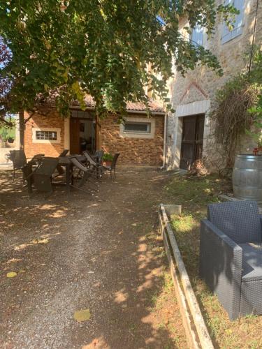 a yard with picnic tables and a building at Les chambres de la P’tite vallée in Anglars-Juillac
