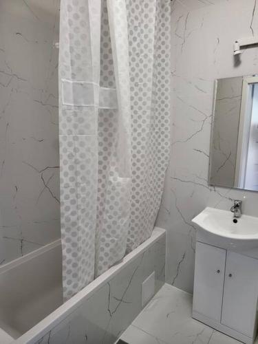 a white bathroom with a shower curtain and a sink at JR APARTMEMT #2 - Slubice Center in Słubice