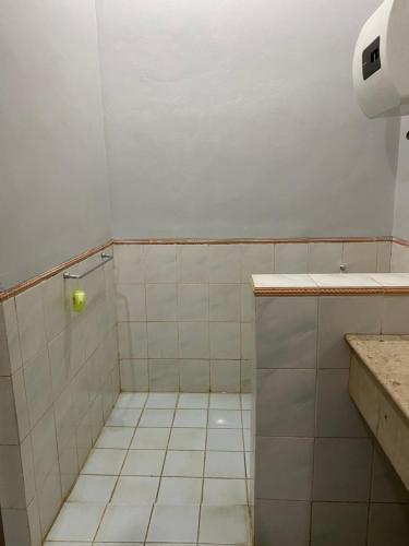 a white tiled bathroom with a shower and a sink at Lippo Carita Ocean View Lantai Dasar by Hello Beach in Carita