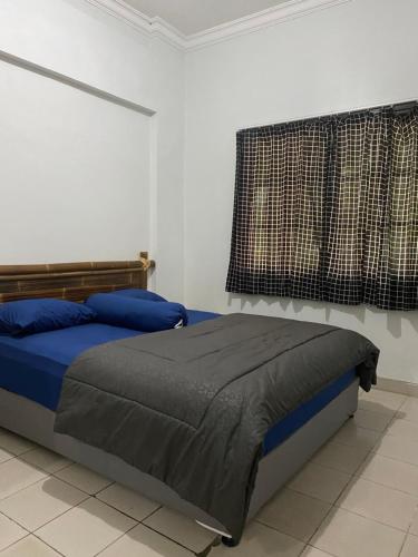 a bedroom with a bed with blue sheets and a window at Lippo Carita Ocean View Lantai Dasar by Hello Beach in Carita
