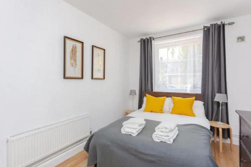 a bedroom with a bed with yellow pillows and a window at Fabulous 2 Bedroom Apartment in London Bridge in London