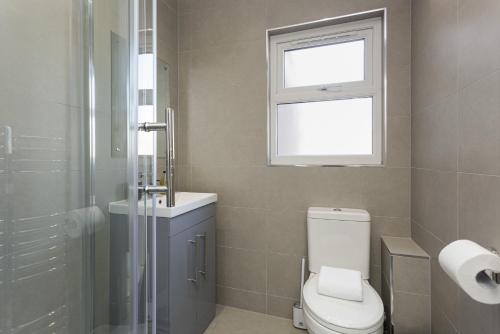 a bathroom with a toilet and a sink and a window at Beatrice Manor - Luxury 4 bedroom house in central Southsea, Portsmouth in Portsmouth