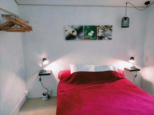 een rood bed in een witte kamer met 2 lampen bij appartement meublé sur la route de Compostelle ! in Aire-sur-lʼAdour