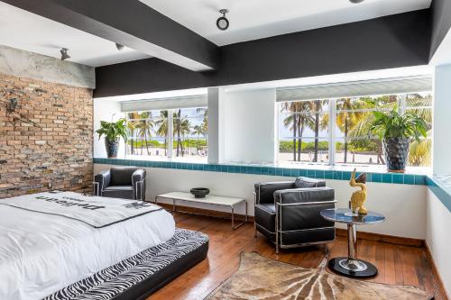 マイアミビーチにあるPelican Hotelのベッドルーム1室(ベッド1台、椅子2脚、窓2つ付)