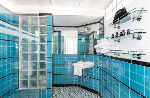 y baño de azulejos azules con lavabo y ducha. en Pelican Hotel, en Miami Beach