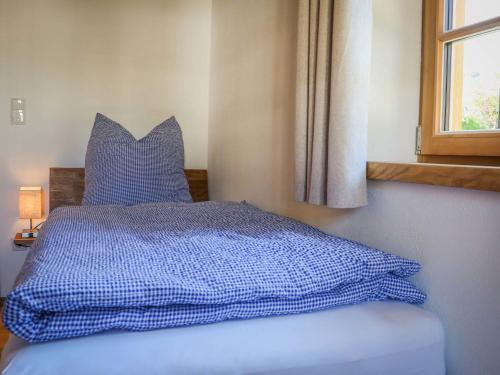 a bed with a blue comforter and a window at Ferienwohnungen Koller in Bad Aibling