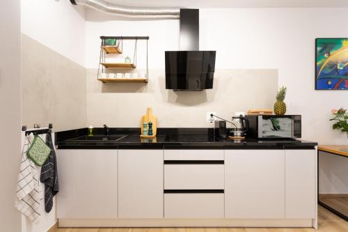 a kitchen with white cabinets and a black counter top at LuxuryCity Apartment with Terrace in Wrocław