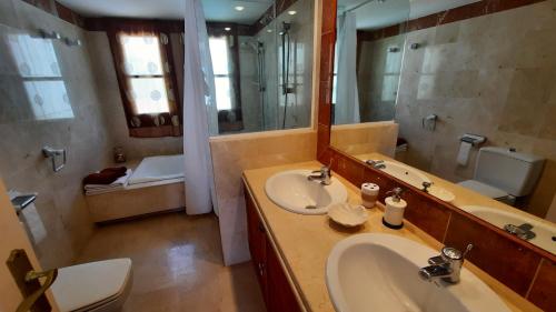 a bathroom with a sink and a toilet and a mirror at Loma del Rey 56 - casa primera linea de mar in Alcaidesa