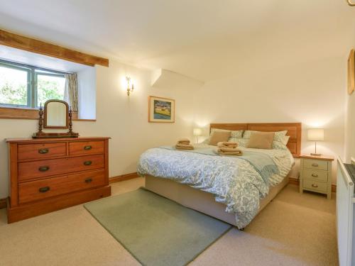 ein Schlafzimmer mit einem Bett mit einer Kommode und einem Spiegel in der Unterkunft Parsonage Farm Cottage in Newton Ferrers