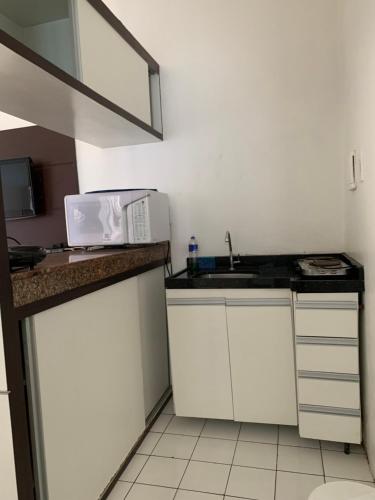una pequeña cocina con fregadero y microondas en Vila Costeira Flat Apto Particular, en Fortaleza