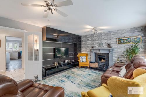 a living room with leather furniture and a fireplace at Silver Stag Properties Large 4 bed Property in Markfield