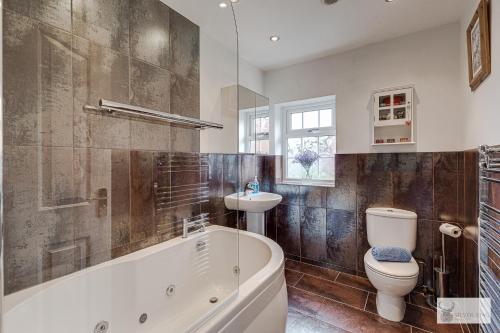 a bathroom with a tub and a toilet and a sink at Silver Stag Properties Large 4 bed Property in Markfield