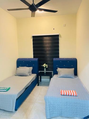 two beds in a room with a ceiling fan at AL Homestay Kajang in Kajang