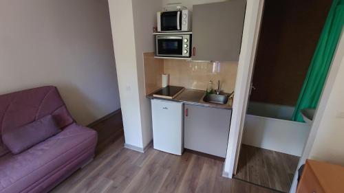 a small room with a couch and a microwave at Residence Les Ecrins in Puy-Saint-Vincent
