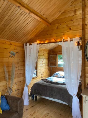 a bedroom with a bed in a wooden cabin at Au chalet Fleuri in Ablon