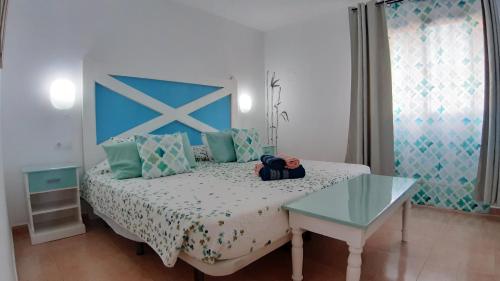 sypialnia z łóżkiem z niebieskim zagłówkiem i stołem w obiekcie Casa Manba, terrace, pool and wifi w Corralejo