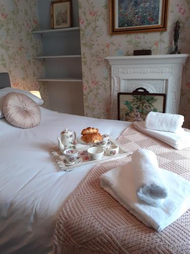 Una cama blanca con una bandeja de comida. en Rose Cottage, en Telford