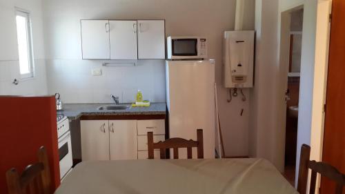a small kitchen with a white refrigerator and a table at Guardalaola in Las Grutas