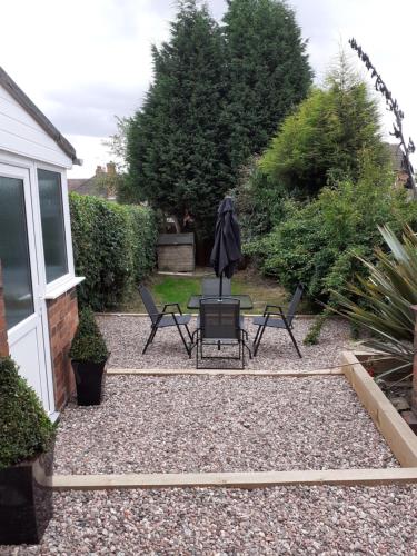 a patio with two chairs and an umbrella in a yard at Rose Cottage in Telford