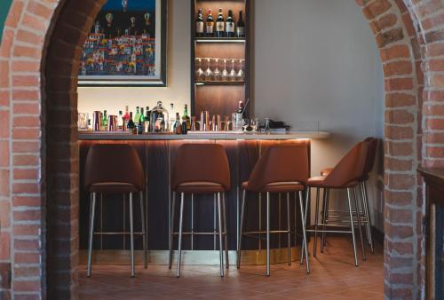 a bar with five brown stools in a room at Borgo San Vincenzo in Montepulciano