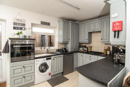 a kitchen with white cabinets and a washer and dryer at ALTIDO Family house with courtyard in Hoylake in Hoylake