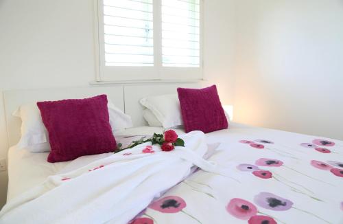 Una cama blanca con almohadas moradas y flores. en Harry's at Spire Cottage Dog friendly cottage, en Chichester