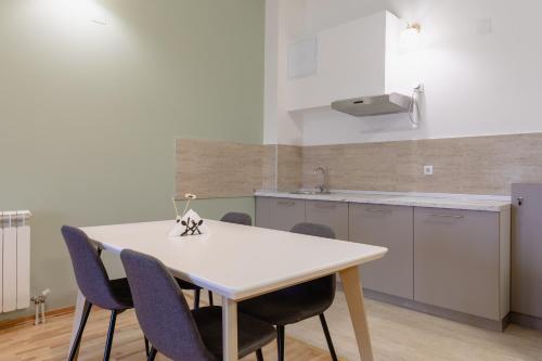 AirMi hotel في Surčin: مطبخ مع طاولة بيضاء وكراسي