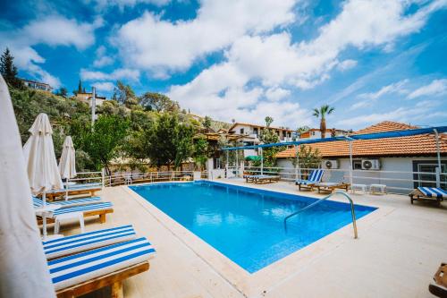 a swimming pool with two chairs and a building at Flower Hotel Patara in Patara