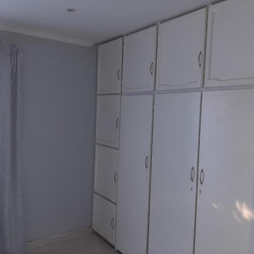 a white closet with white cabinets in a room at The Cradle's Rest Guest House in Krugersdorp