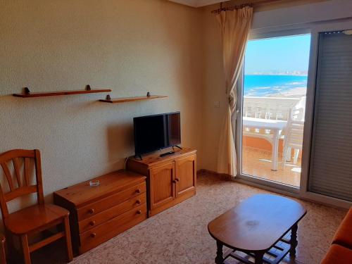 sala de estar con TV, silla y ventana en Apartamentos Turísticos Isla Grosa, en La Manga del Mar Menor