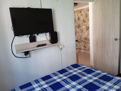 a bedroom with a tv on a wall with a bed at Apartamento Quintas de San Javier in Medellín