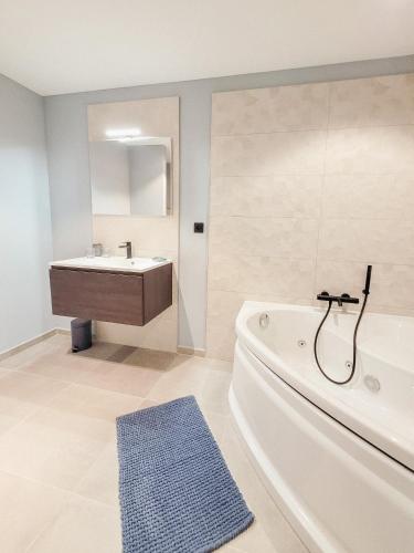 a bathroom with a bath tub and a sink at Au bout de mes rêves in Walcourt