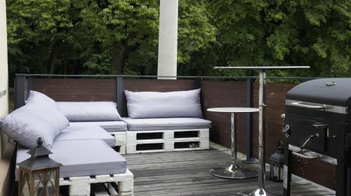 a patio with a grill and a couch and pillows at Fantazja Góra Św Anny in Góra Świętej Anny