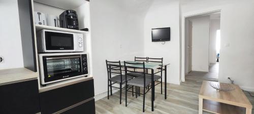 une cuisine avec une table avec des chaises et un micro-ondes dans l'établissement Appartement Le république idéalement situé., à Saint-Ambroix
