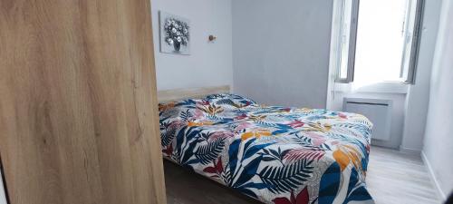 1 dormitorio con 1 cama con colcha de flores en Appartement Le république idéalement situé., en Saint-Ambroix