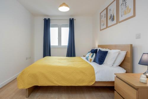 ein Schlafzimmer mit einem Bett mit einer gelben Decke in der Unterkunft Cloud9SA at The Park Heights Woking in Woking